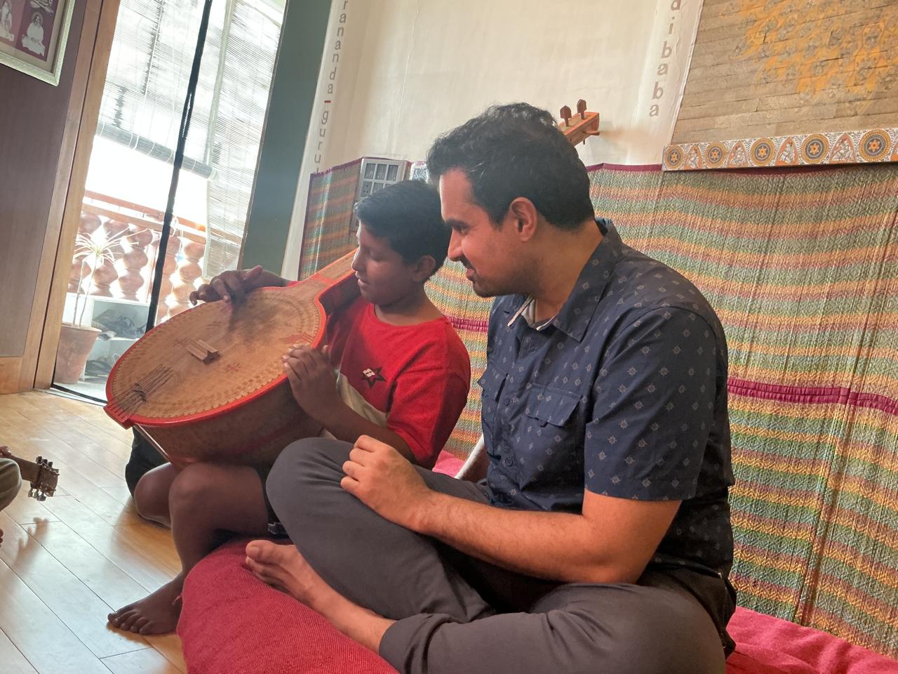 Priyal helping a child explore a traditional string instrument
